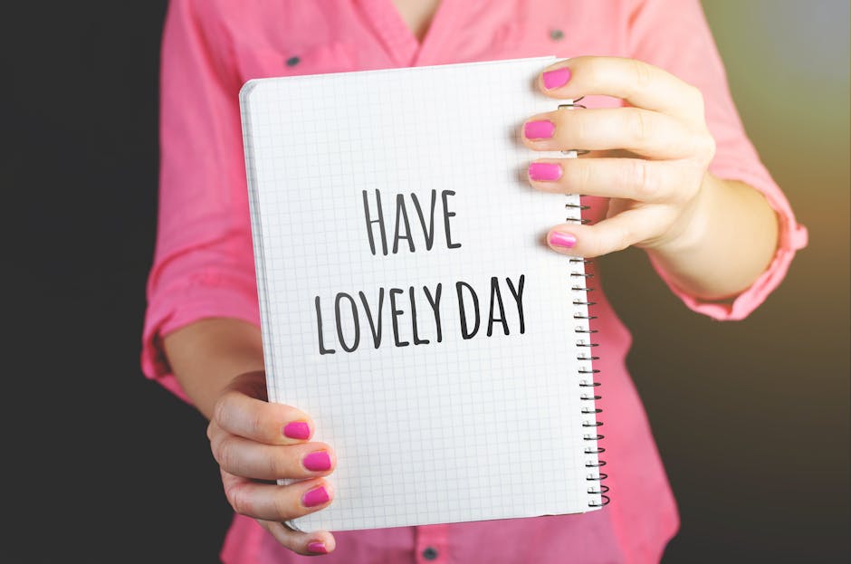 A woman in a pink shirt holds a notebook displaying 'Have a Lovely Day', conveying positivity